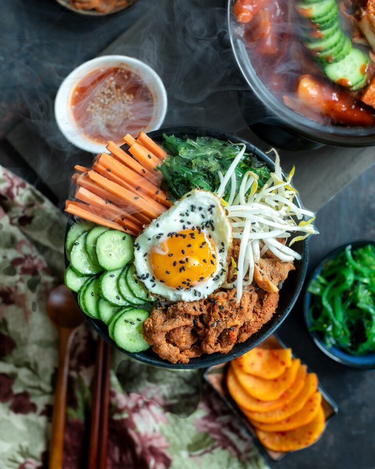 A bowl of food with carrots, cucumbers and other vegetables